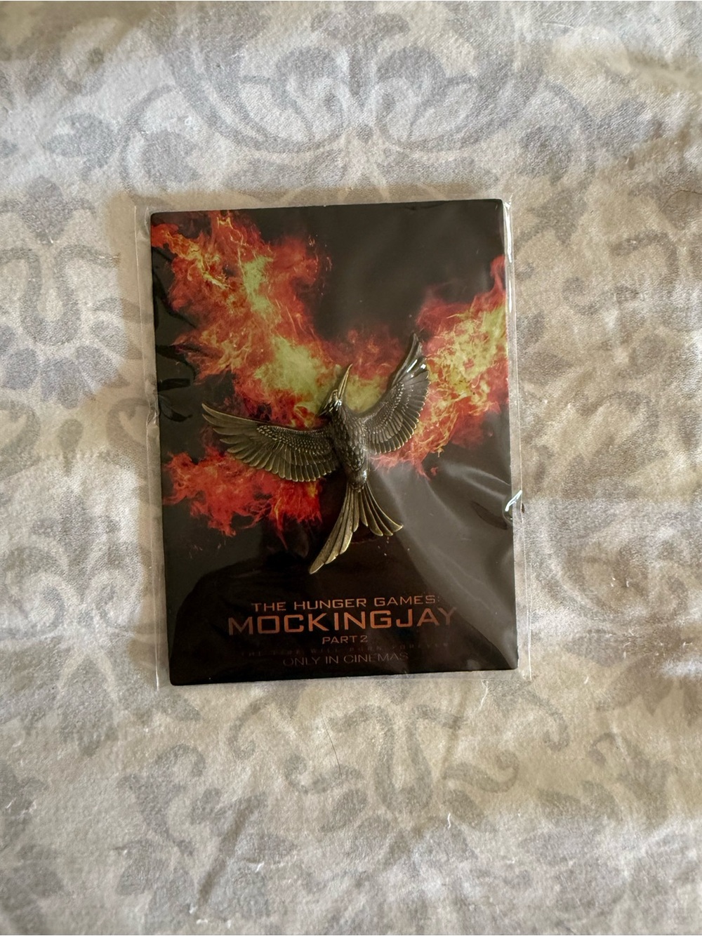 The Hunger Games Mockingjay Pin - Metallic Gold on Black & Fiery Background